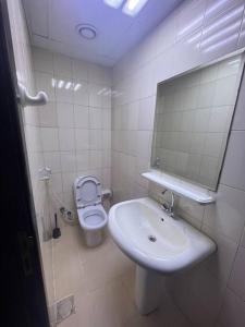 a white bathroom with a sink and a toilet at Cozy 1Bhk with stunning sea view in Sharjah