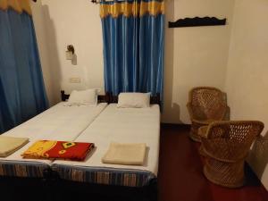a bedroom with a bed with blue curtains and two chairs at Marari Beach Homestay in Mararikulam