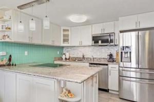 a kitchen with white cabinets and stainless steel appliances at Beautiful Condo Right on the Beach in Hauula