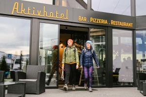 a man and woman walking out of a building at Hotel Wochtla Buam in Brunico