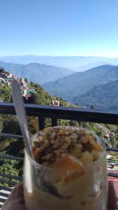 eine Hand, die eine Tasse Essen mit einem Löffel hält in der Unterkunft Rap's Den in Darjeeling