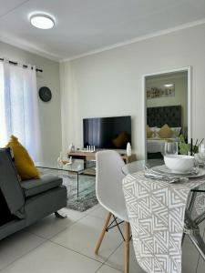 a white living room with a table and a couch at Flat in Midrand in Midrand