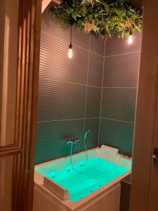 uma casa de banho com uma banheira com água azul em SUITE Serenity Room SPA- Balnéothérapie em Saint-Étienne