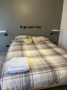 una cama con un edredón a cuadros con un mensaje en la pared en Ampio bilocale con giardino privato a due passi dalla stazione, en Carnate
