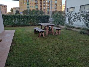 una mesa de picnic y dos bancos en un patio en Ampio bilocale con giardino privato a due passi dalla stazione, en Carnate