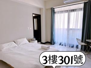 a white bed in a room with a large window at 補夢網民宿 in Donggang