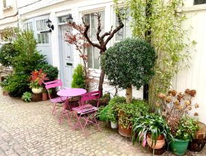 um pátio com uma mesa rosa, cadeiras e plantas em London Choice Apartments - South Kensington - Mews House em Londres