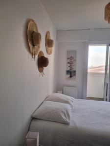 sypialnia z łóżkiem z kapeluszami na ścianie w obiekcie Eau Bleue d'Eden w mieście Saint-Hilaire-de-Riez