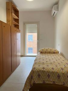 a bedroom with a bed and a large window at MAISON ANZIO E ROSA in Ravenna