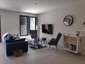 a living room with a couch and chairs and a tv at L'Orée des Alpilles Proche Centre ville St Rémy de Provence in Saint-Rémy-de-Provence