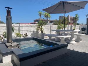 a swimming pool with a table and an umbrella at Strand Stay in Strand