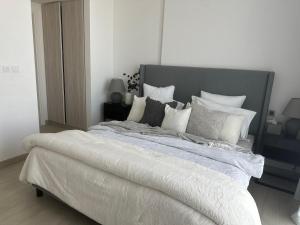 a bedroom with a large bed with white sheets and pillows at Modern Sanctuary W/ Pool & Gym access in Sharjah