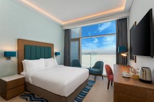 ドバイにあるPark Regis by Prince Dubai Islandsのベッドと大きな窓が備わるホテルルームです。