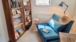 uma sala de estar com um sofá azul e uma estante de livros em Gite du Four à Pain 4* - Le Domaine des Cyclamens em Verneuil-sur-Indre