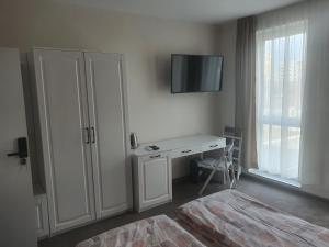 a bedroom with a desk and a tv on the wall at Димоти Апартхотел in Sofia