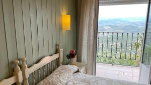 ein Schlafzimmer mit einem Bett und einem großen Fenster in der Unterkunft La Finca Mercedes in La Iruela