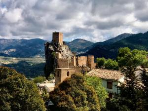un antiguo castillo en la cima de una colina con montañas en La Finca Mercedes en La Iruela
