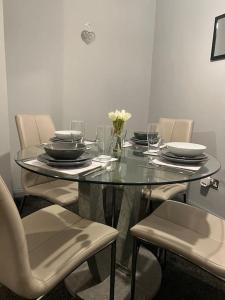 d'une table en verre avec des chaises, des assiettes et des fleurs. dans l'établissement Washington Residence, à Usworth