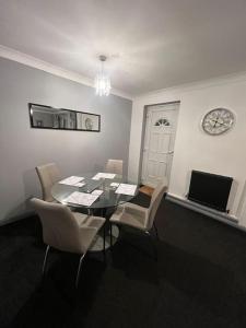 Washington Residence في Usworth: غرفة طعام مع طاولة وكراسي وساعة