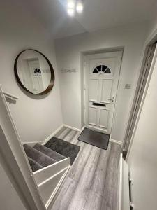 a hallway with a white door and stairs with a mirror at Nice & Cozy Furnished 1 Bedroom Flat in Luton