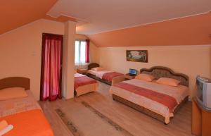 a hotel room with three beds and a television at Guest house Vila Bor in Novi Sad