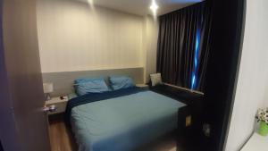 a small bedroom with a blue bed and a window at The Prio Condo in Chiang Mai