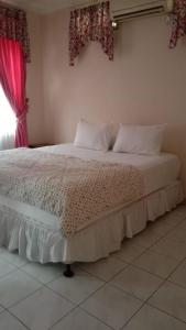 a bed in a bedroom with a pink window at Villa Kota Bunga Puncak Bogor in Cimacan
