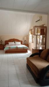 een slaapkamer met een bed en een bank in een kamer bij Villa Kota Bunga Puncak Bogor in Cimacan