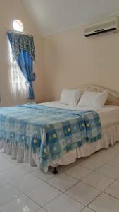 a bedroom with a bed with a blue blanket on it at Villa Kota Bunga Puncak Bogor in Cimacan