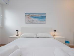 un letto bianco in una camera bianca con due lampade di [IHost Flat] - Giambellino 131-2 a Milano