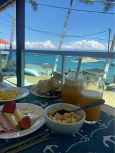 a table with plates of food and drinks and a view of the ocean at Encanto do Mar in Praia de Araçatiba