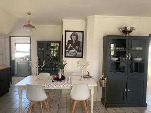 een keuken met een witte tafel en witte stoelen bij Strand Stay in Strand