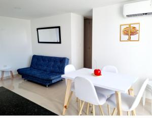 a dining room with a white table and a blue couch at Apartamento de descanso Om Shanti Om in Coveñas