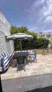 un patio con sombrilla, mesa y sillas en Maison avec jardin à 2 minutes à pied de la plage en Temara