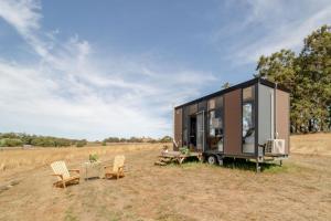 a tiny house with a table and chairs in a field at Tiny Divine Farmstay in Korweinguboora