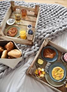 a breakfast tray with breakfast foods and drinks on a bed at ZeeLand & Meer in Kamperland