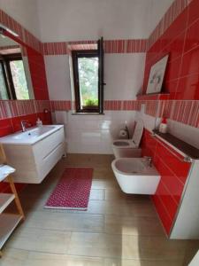 a red and white bathroom with two toilets and a sink at Agrifoglio B&B con giardino in Aritzo +9 photos