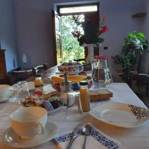 einen Tisch mit Tellern und Tassen und Geschirr darauf in der Unterkunft Agrifoglio B&B con giardino in Aritzo