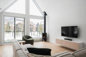uma sala de estar com 2 sofás e uma televisão de ecrã plano em Villas Perspective-Amandine-Mont-Sainte-Anne em Beaupré