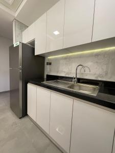 eine weiße Küche mit einer Spüle und einem Kühlschrank in der Unterkunft Oval Tower Business Bay in Dubai