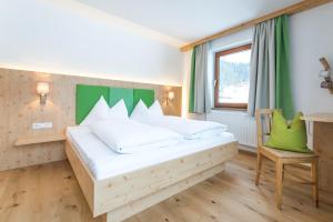 Un dormitorio con una cama grande y una silla. en Landhaus Sunseitn, en Ramsau am Dachstein