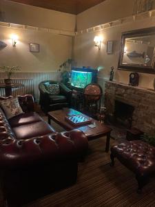 a living room with a leather couch and a television at The Bridge Inn in Reeth