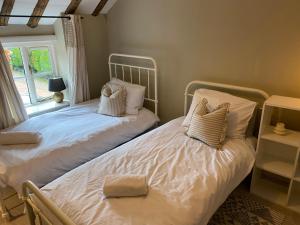2 camas individuales en una habitación con ventana en Stone Cottage en Norwich