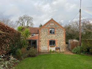 une ancienne maison en briques avec une pelouse devant elle dans l'établissement Stone Cottage, à Norwich
