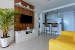 a living room with a tv and a yellow couch at Casa da Geo Ondina - Frente de Praia in Salvador