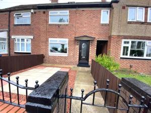 a brick house with a black door and a fence at OG Tranquil Homes - Contractor & Family Friendly, FREE WiFi & Parking, Laptop friendly, Garden in Sunderland