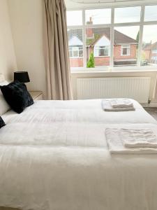 a white bed in a bedroom with a large window at Immaculate 3-Bed Travel nest unavailable in Manchester