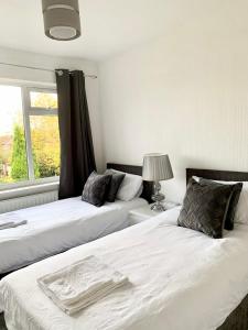 dos camas sentadas una al lado de la otra en un dormitorio en Immaculate 3-Bed Travel nest unavailable, en Mánchester