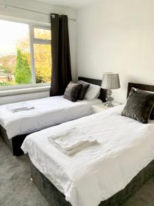 two beds in a room with a window at Immaculate 3-Bed Travel nest unavailable in Manchester