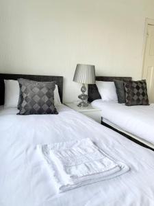 1 dormitorio con 2 camas y manta blanca en Immaculate 3-Bed Travel nest unavailable, en Mánchester